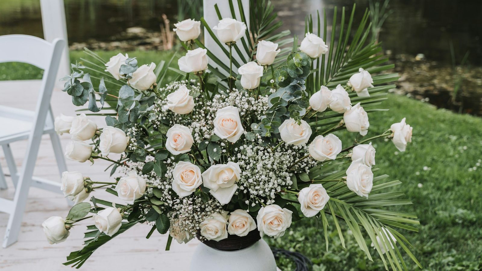 Arrangement of white roses and greenery for sympathy